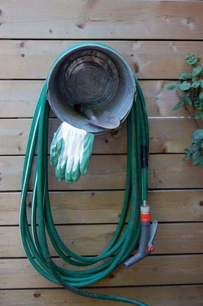 Creative Hose Storage Solution with a Fence-Mounted Bucket