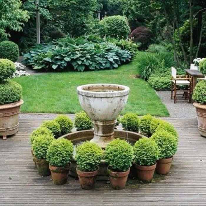 Vessel Fountain Surrounded by Terracotta Hedge